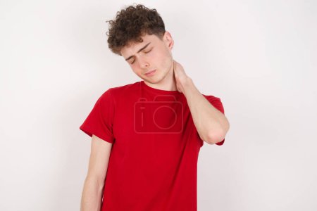Foto de Joven guapo sobre fondo blanco que sufre de lesión dolor de espalda y cuello, tocando el cuello con la mano, dolor muscular. - Imagen libre de derechos