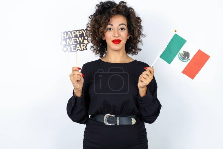 Foto de Mujer hermosa joven con el pelo rizado con vestido negro, bandera de México y una bandera feliz año nuevo 2024 - Imagen libre de derechos