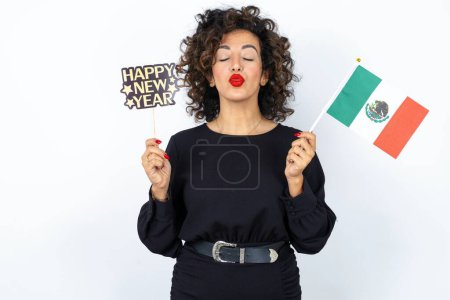 Photo for Young beautiful woman with curly hair wearing black dress, Mexico flag and a Happy new year 2024 banner - Royalty Free Image