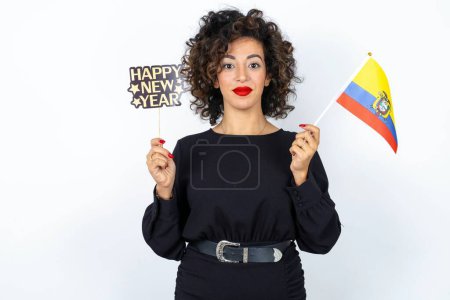 Photo for Young beautiful woman with curly hair wearing black dress, Ecuador flag and a Happy new year 2024 banner - Royalty Free Image