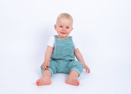 Photo for Studio portrait of cute little kid boy wearing green overall posing over white studio background - Royalty Free Image