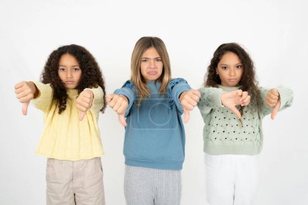 Foto de Tres adolescentes siendo molesto mostrando el pulgar hacia abajo con dos manos. Concepto de aversión. - Imagen libre de derechos