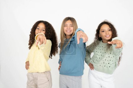 Téléchargez les photos : Trois adolescentes pointant vers la caméra avec un sourire satisfait, confiant et amical, vous choisissant - en image libre de droit