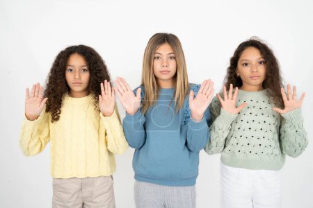 Foto de Serious tres chicas adolescentes tira de las palmas de las manos hacia la cámara, hace gesto de parada, pide controlar sus emociones y no estar nervioso - Imagen libre de derechos