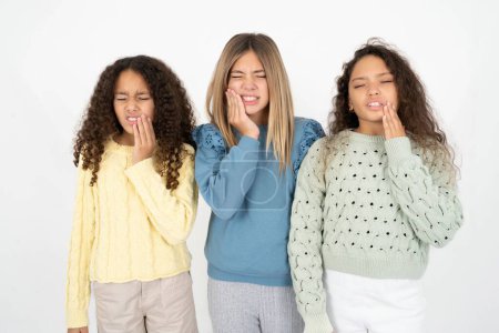 Téléchargez les photos : Trois adolescentes touchant la bouche avec la main avec une expression douloureuse à cause de maux de dents ou de maladies dentaires sur les dents. - en image libre de droit