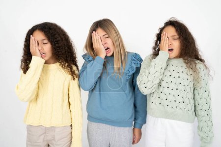 Foto de Tres chicas adolescentes bostezando cansadas cubriendo media cara, ojo y boca con la mano. La cara duele de dolor. - Imagen libre de derechos
