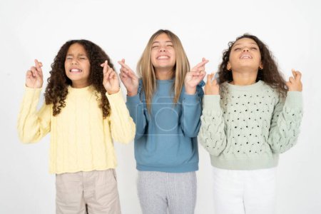 Téléchargez les photos : Trois adolescentes geste doigt croisé souriant avec espoir et les yeux fermés. La chance et le concept superstitieux. - en image libre de droit