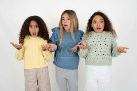 Photo for Frustrated three teenager girls feels puzzled and hesitant, shrugs shoulders in bewilderment, keeps mouth widely opened, doesn't know what to do. - Royalty Free Image