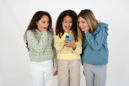 Foto de Tres chicas adolescentes sosteniendo en las manos la lectura de la célula sms utilizando la nueva aplicación 5g - Imagen libre de derechos