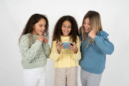 Foto de Tres chicas adolescentes sosteniendo en las manos de la célula jugando videojuegos o charlando - Imagen libre de derechos