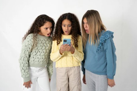 Foto de Sorprendió a tres adolescentes usando teléfonos inteligentes leyendo noticias de redes sociales, o correo electrónico importante - Imagen libre de derechos