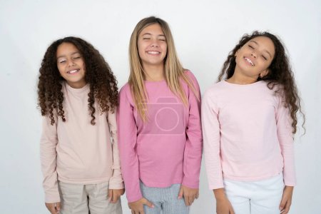 Téléchargez les photos : Positif trois adolescentes avec une expression ravie ferme les yeux et rit montre dents blanches parfaites - en image libre de droit
