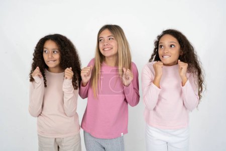 Photo for Three teenager girls clenches fists and awaits for something nice happened looks away bites lips and waits announcement of results - Royalty Free Image