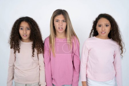 Téléchargez les photos : Portrait de trois adolescentes insatisfaites sourit visage, porte-monnaie lèvres et regarde avec agacement à la caméra, mécontentement entendre quelque chose de désagréable - en image libre de droit