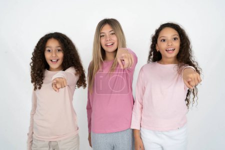 Photo for Excited positive three teenager girls points index finger directly at you, sees something very funny. Wow, amazing - Royalty Free Image