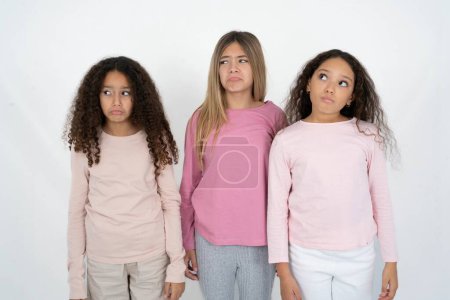Photo for Dissatisfied three teenager girls purses lips and has unhappy expression looks away stands offended. Depressed frustrated model. - Royalty Free Image