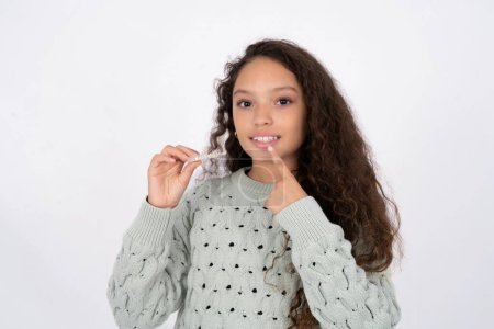 Foto de Joven hermosa adolescente sosteniendo un alineador de frenos invisibles, recomendando este nuevo tratamiento. Concepto de salud dental. - Imagen libre de derechos