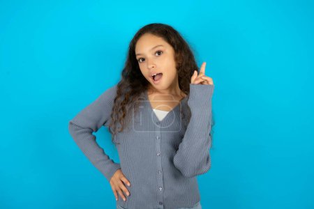 Photo for Teenager girl wearing grey sweater against blue background holding finger up having idea and posing - Royalty Free Image