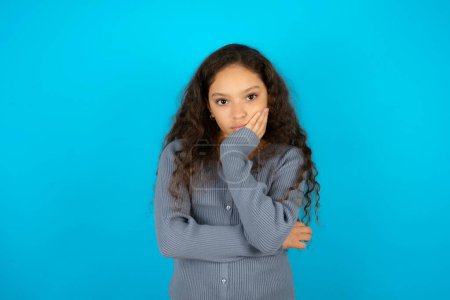 Photo for Very bored Teenager girl wearing grey dress against white background  holding hand on cheek while support it with another crossed hand, looking tired and sick, - Royalty Free Image