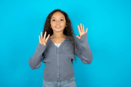 Téléchargez les photos : Adolescente portant un pull gris sur fond bleu montrant et pointant vers le haut avec les doigts numéro neuf tout en souriant confiant et heureux. - en image libre de droit