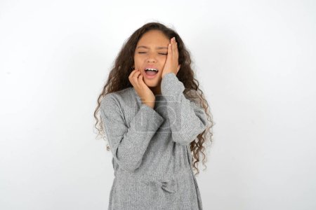 Photo for Doleful desperate crying teenager girl wearing grey sweater , looks stressfully, frowns face, feels lonely and anxious - Royalty Free Image