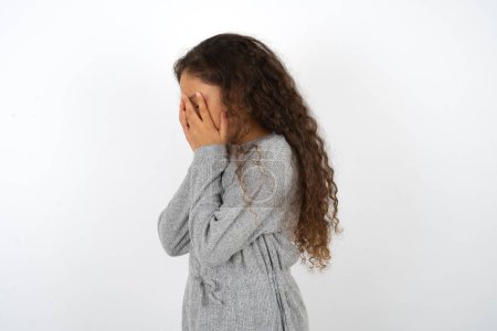 Téléchargez les photos : Triste adolescente portant un pull gris pleurant couvrant son visage avec ses mains. - en image libre de droit