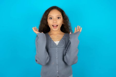 Surprised terrified teenager girl wearing grey sweater Gestures with uncertainty, stares at camera, puzzled as doesn't know answer on tricky question, People, body language, emotions concept
