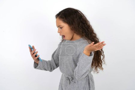 Photo for Angry teenager girl wearing grey sweater screaming on the phone, having an argument with an employee. Troubles at work. - Royalty Free Image