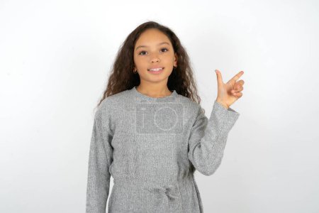 Foto de Adolescente chica usando gris suéter apuntando hacia arriba con los dedos número ocho en chino lenguaje de signos B. - Imagen libre de derechos