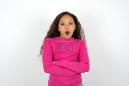 Photo for Shocked embarrassed teenager girl wearing pink sweater keeps mouth widely opened. Hears unbelievable novelty stares in stupor - Royalty Free Image