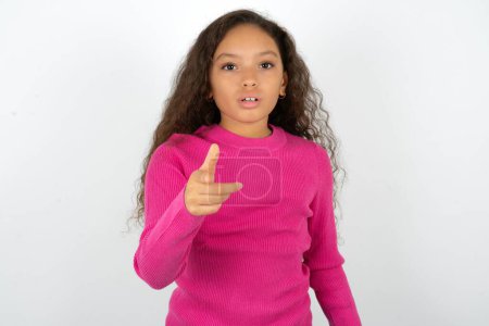 Téléchargez les photos : Ado choqué fille portant des points de pull rose à vous avec une expression stupéfaite - en image libre de droit