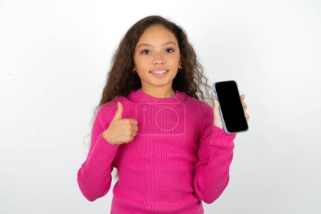 Foto de Adolescente chica usando suéter rosa Mostrar pantalla en blanco smartphone, pulgar hacia arriba recomendar nueva aplicación - Imagen libre de derechos