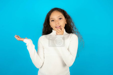 Photo for Positive teenager girl wearing white sweater advert promo touch finger teeth - Royalty Free Image