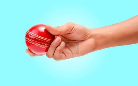 Téléchargez les photos : Poignée Bowler mâle à l'essai rouge brillant boule de cricket gros plan photo sur fond bleu doux - en image libre de droit