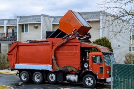 Foto de Big garbage truck picking up trash wagon car - Imagen libre de derechos