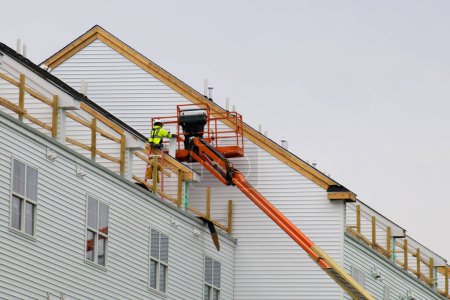 Téléchargez les photos : A worker installs panels siding on the facade of the house wall vinyl material - en image libre de droit