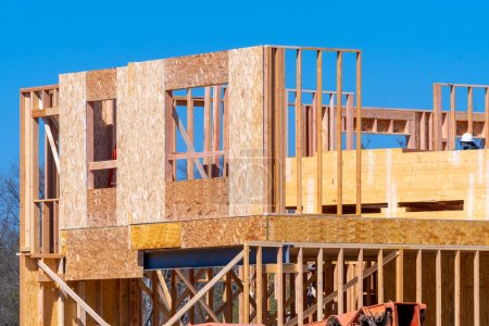 Foto de Estructura de marco de madera en el nuevo sitio de desarrollo inmobiliario nueva casa actualmente en construcción contra el material de madera contrachapada cielo azul - Imagen libre de derechos