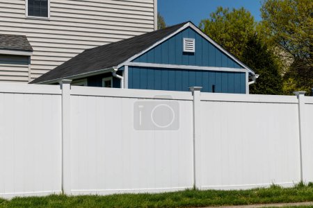 white vinyl picket fence on green lawn surrounding property grounds for backyard protection and privacy wall