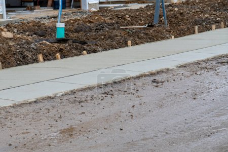 residential community construction site, freshly poured concrete sidewalk and fresh dirt industry material