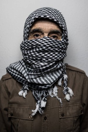 Téléchargez les photos : Portrait d'un militaire portant un foulard ou un shemagh palestinien, couvrant son visage, sur fond blanc. Concept de milicien, terrorisme, guerre, Palestine, Israël, terreur, peur, insécurité, conflit. - en image libre de droit