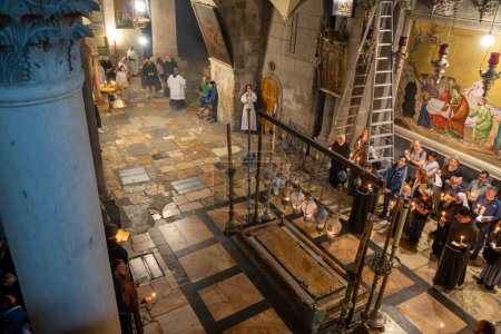 Foto de Jerusalén, Israel - 10 de abril de 2023. Sacerdotes, Turistas y peregrinos oran en la Piedra de la Unción en la iglesia del sepulcro sagrado - Imagen libre de derechos