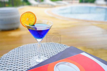 Téléchargez les photos : Une boisson rafraîchissante à base de soda aux myrtilles avec un peu d'orange sur le verre. boisson de vacances Détendez-vous au bord de la piscine sur le toit de l'un des hôtels en Thaïlande. - en image libre de droit