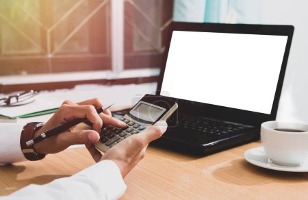 hombre de negocios usando calculadora calculando dinero digital con maqueta portátil y café en la mesa de escritorio en la oficina en casa por la mañana.