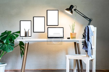 Photo for Home office with laptop mockup and chair, document book on table decor white frame as lamp light and monstera tree pot plants house nature wall modern loft interior decorations workspace. - Royalty Free Image
