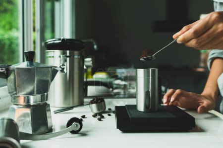Pulverkaffee auf einem Edelstahllöffel mit der Hand Menschen gießen Röstkaffee für Espresso-Kaffee in die Tasse mit Ausrüstung Werkzeug Brauen italienischen Mokka-Kanne, Kaffee in der Küche zu Hause. Zubereitungsdrink