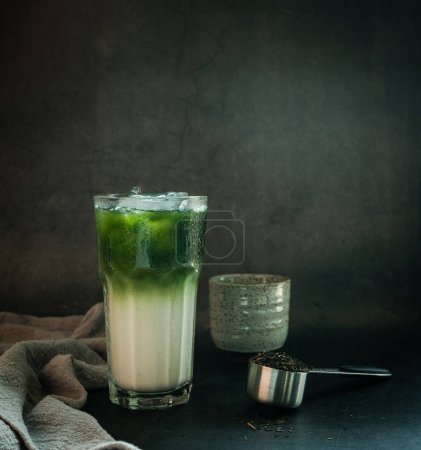 Téléchargez les photos : Thé vert Matcha sur le dessus lait dans un verre sur un fond noir studio photo Copier l'espace pour le texte - en image libre de droit