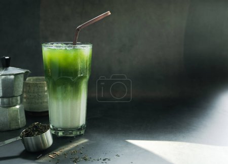 Photo for Iced Matcha green tea with Italian Moka pot coffee equipment to brew and powdered green tea on a spoon. light, black background. copy space for your text - Royalty Free Image
