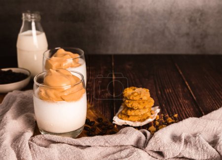 Photo for Iced or Frothy Coffee Milk on glass cup and cornflakes, oat cookie, Roasted coffee beans on wooden table - Royalty Free Image