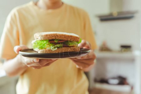Photo for Hand people holding a delicious homemade breakfast sandwich with ham, fried egg and green, Cos Lettuce vegetable . healthy food selective focus - Royalty Free Image