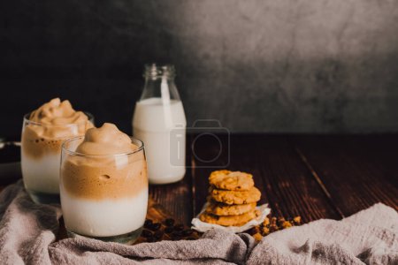 Photo for Iced or frappe coffee cup and cookie, milk bottle on the wood table on black marble background. Copy space for your text. - Royalty Free Image